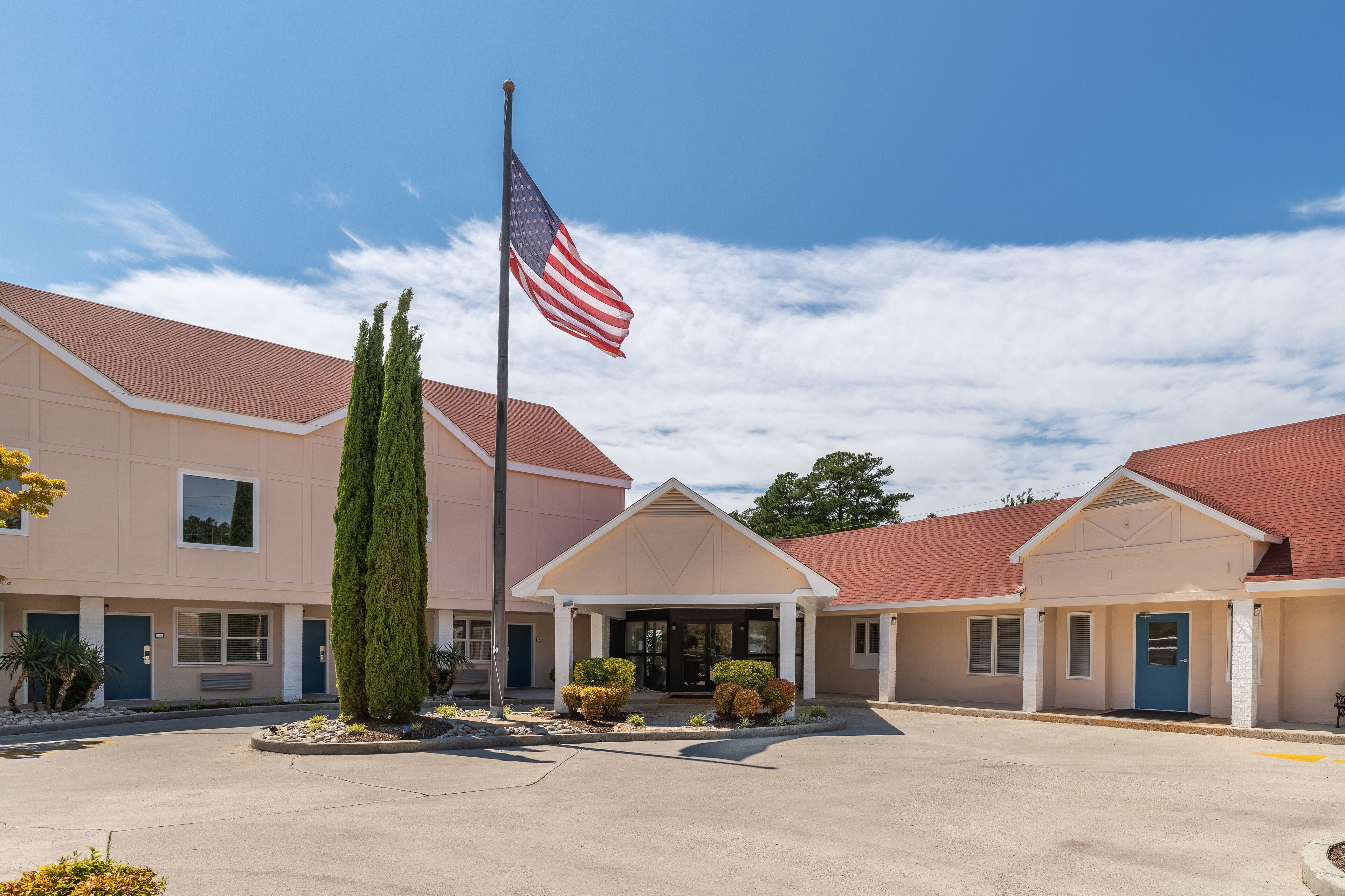A building with a flagpole, a blue entrance, and a red roof.