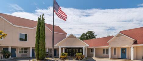 A building with a flagpole, a blue entrance, and a red roof.