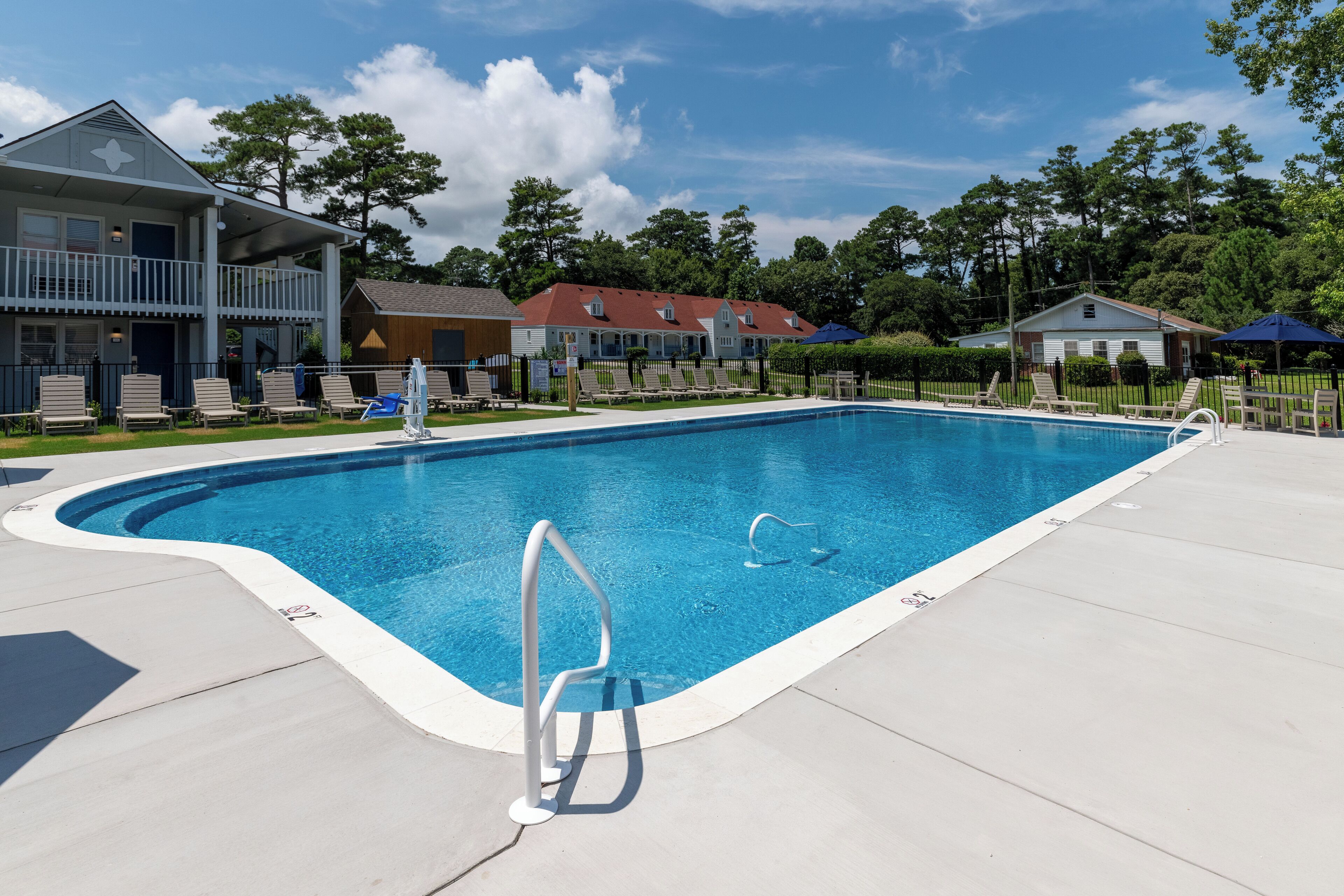 A rectangular swimming pool with a metal ladder, surrounded by a concrete deck.