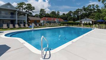 A rectangular swimming pool with a metal ladder, surrounded by a concrete deck.