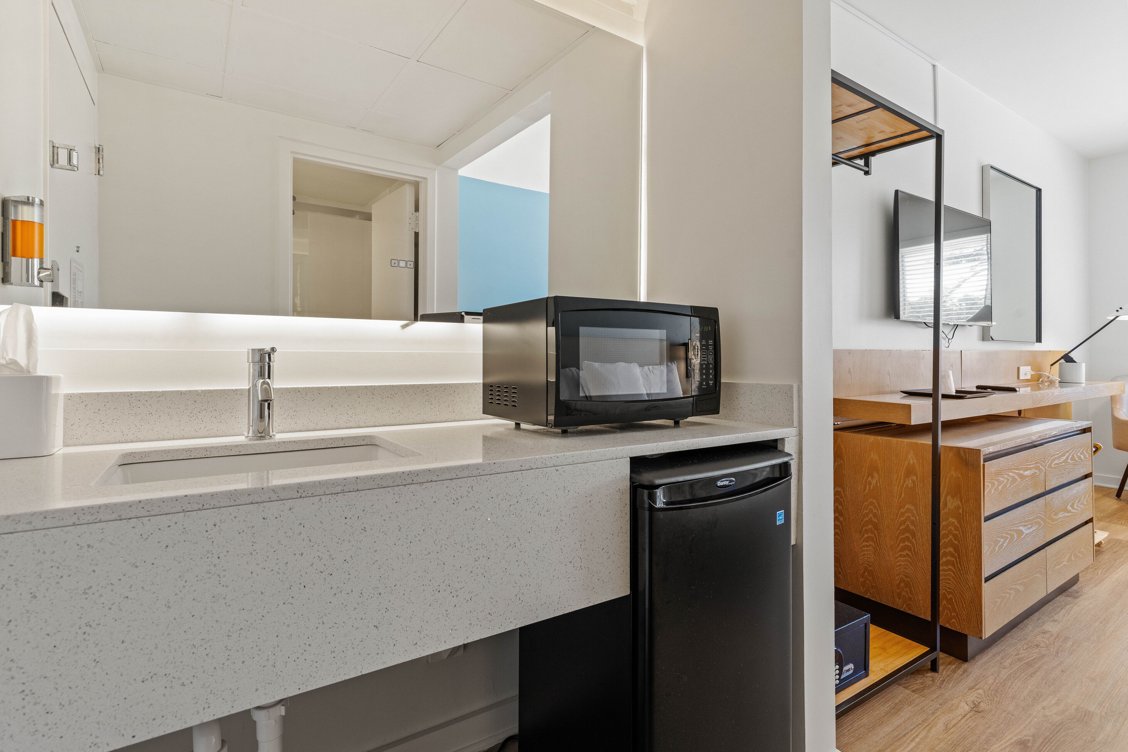A modern kitchen with a built-in microwave, a sink, and a compact refrigerator.