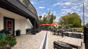 Un patio al aire libre con mesas, sillas, un extintor y plantas en macetas.