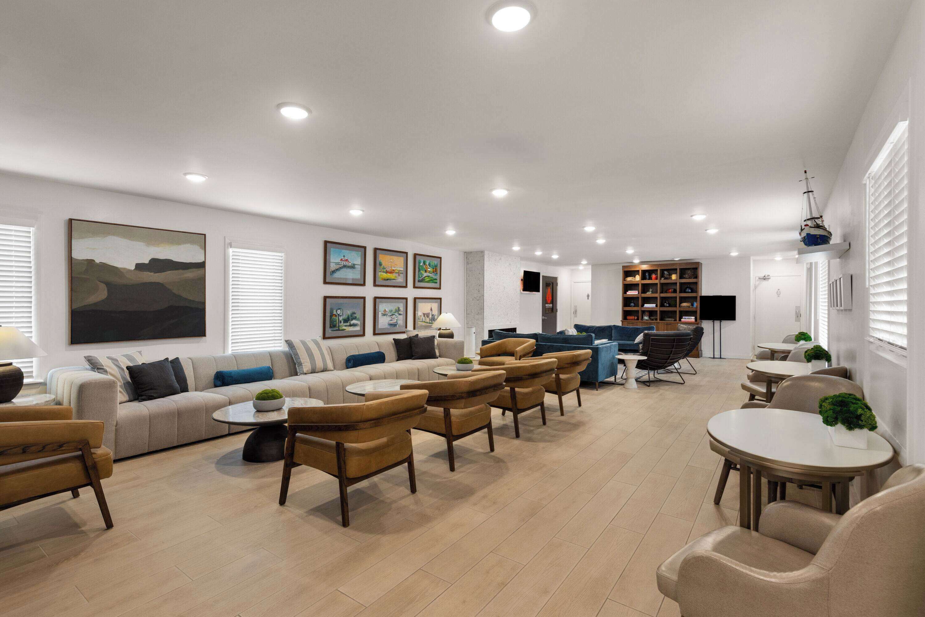 A spacious living room with a sofa set, armchairs, a coffee table, and a bookshelf.