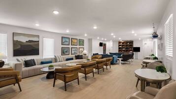 A spacious living room with a sofa set, armchairs, a coffee table, and a bookshelf.
