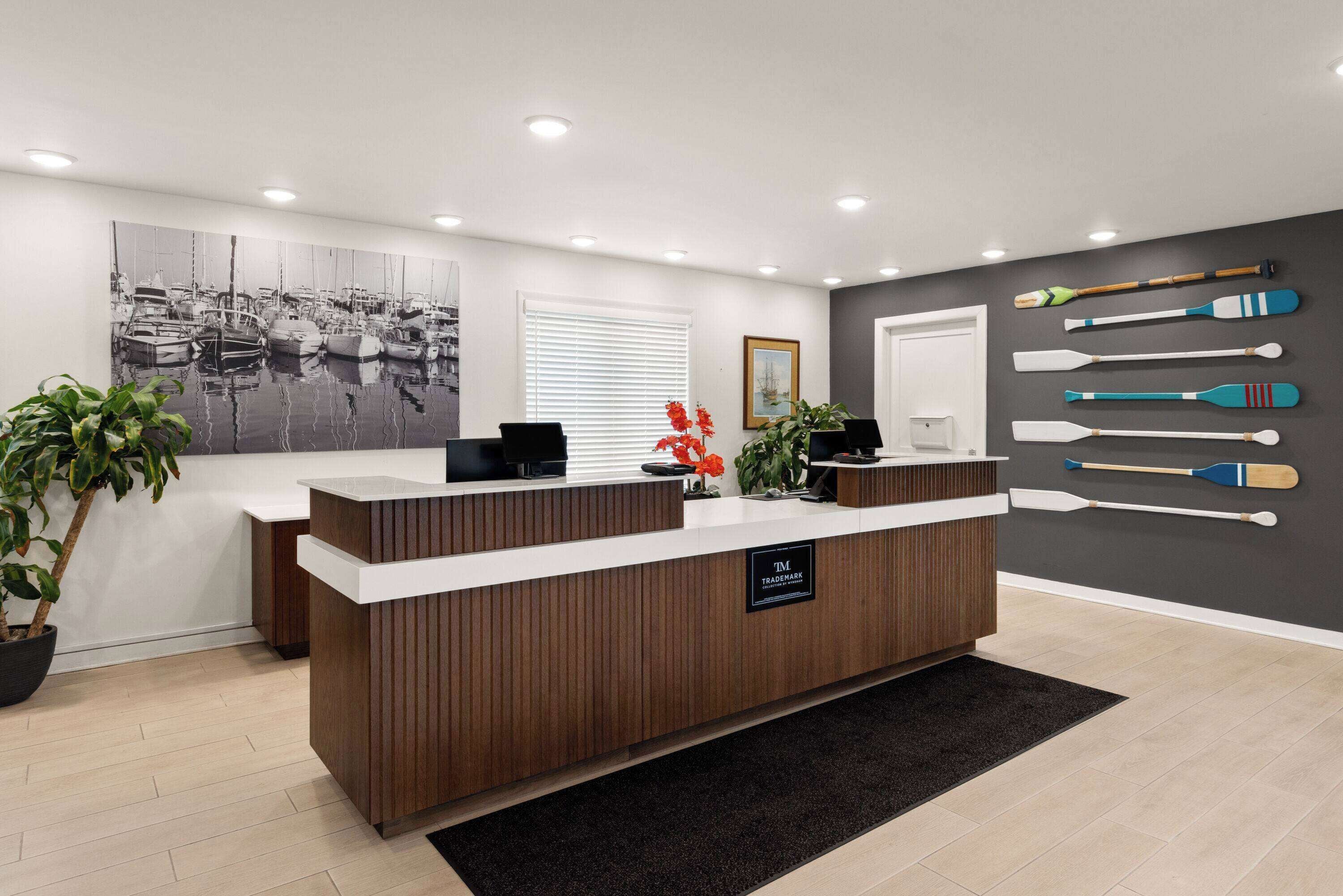 A reception desk with a modern design, a large black and white photograph on the wall, and several paddles displayed on the wall.
