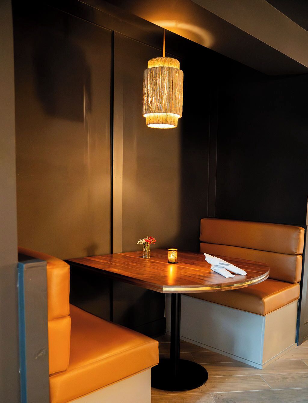 Un espace repas moderne avec une table en bois, des sièges rembourrés et un luminaire suspendu.