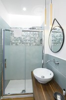 A modern bathroom with a glass shower enclosure, a white sink, and a mirror on the wall.