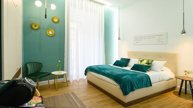 A modern bedroom with a bed, a chair, a small table, and a wall with decorative elements. - Annapoli Rooms (Naples)
