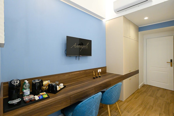 A hotel room with a wooden desk, a flat-screen TV, and a minibar.