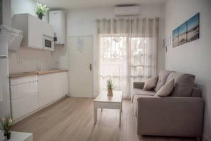 Een modern appartement met een kitchenette, een zithoek met een bank en een eettafel.