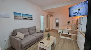 A modern living room with a sofa, a coffee table, and a TV mounted on the wall.