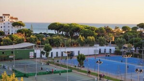 Ett sportkomplex med flera tennisbanor, omgivet av grönska och byggnader.