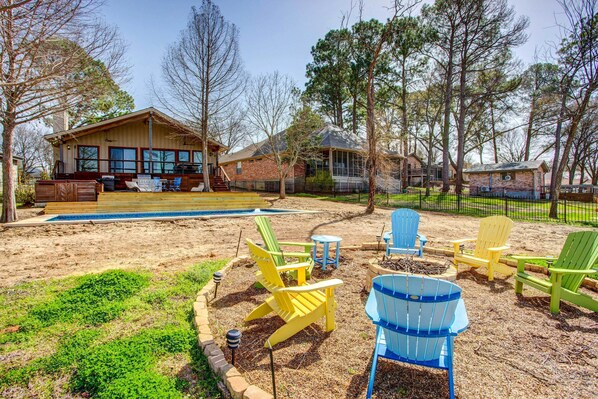 A backyard with a wooden deck, outdoor seating, and a swimming pool. - Cedar Creek Lakefront Vacation Rental w/ Pool (Gun Barrel City)