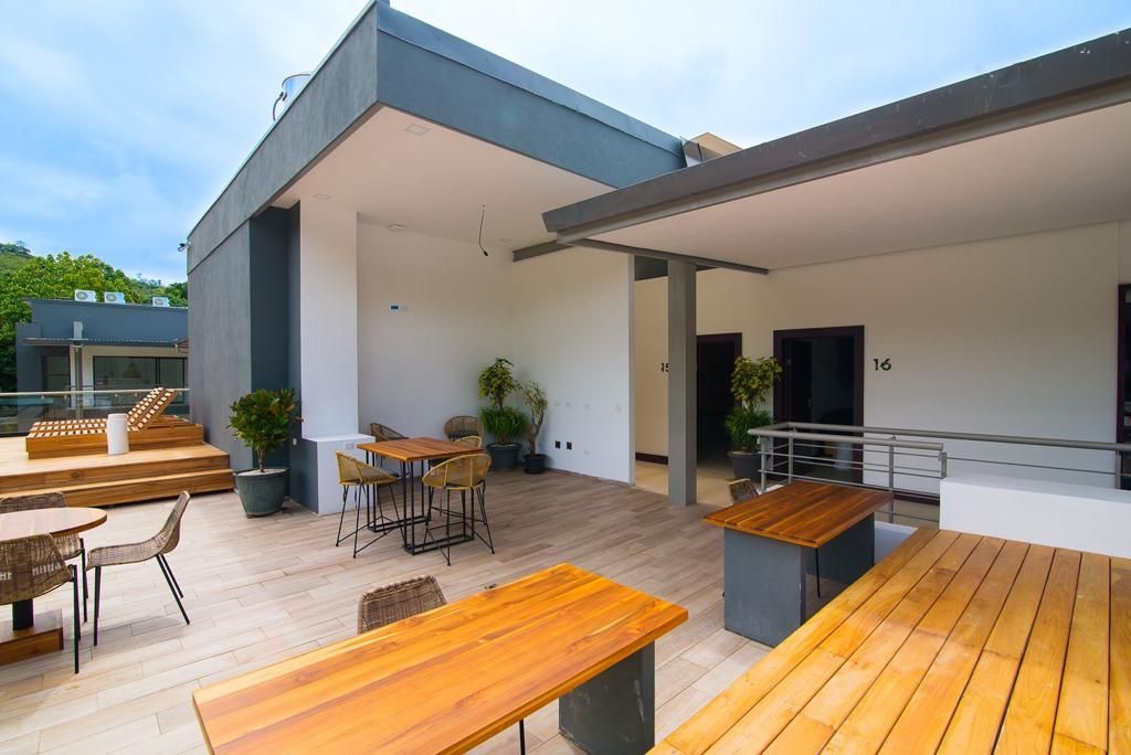 An outdoor patio area with wooden tables and chairs, potted plants, and a modern architectural design.