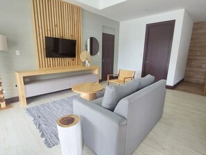 A modern living room with a grey sofa, wooden entertainment unit, and a round coffee table.