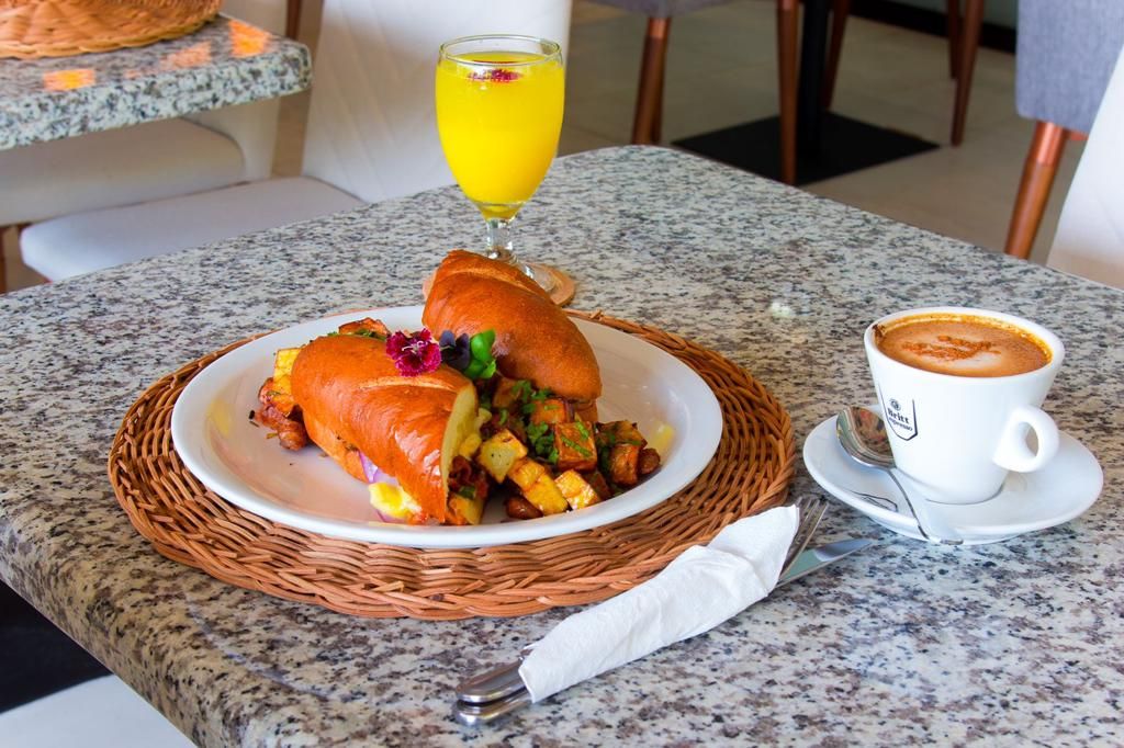 Frühstückstisch mit Speisen, Orangensaft und einer Tasse Kaffee auf einer Marmortafel.