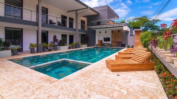 Uma casa moderna com piscina, área de estar externa e plantas em vasos.