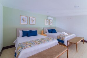 Una habitación de hotel con dos camas, una mesita pequeña y un banco.