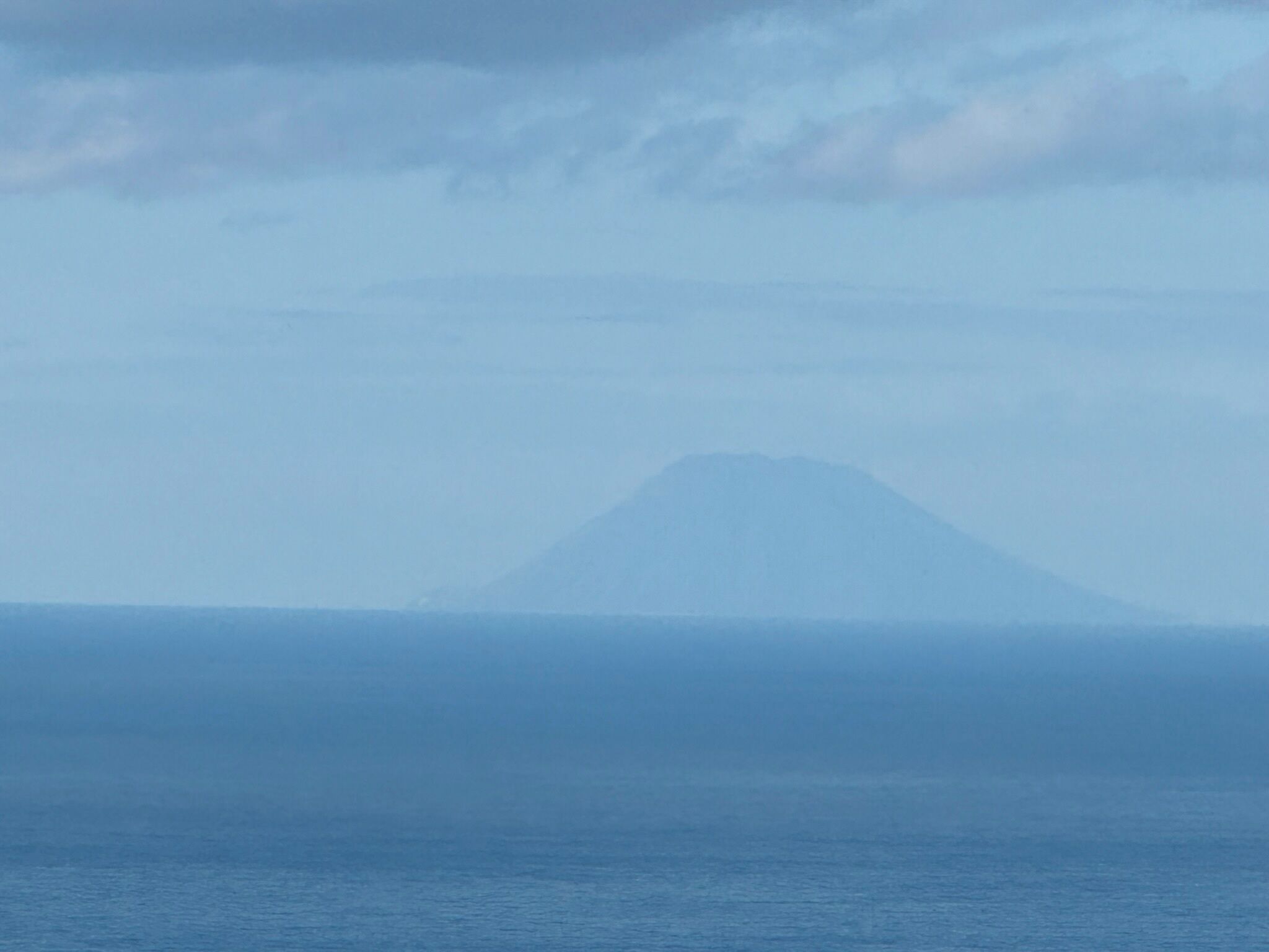 Vista d'una muntanya sobre un mar tranquil.