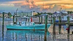 A boat docked at a marina with a sunset in the background. - The Orange Door - Coastal Escape (Stuart)