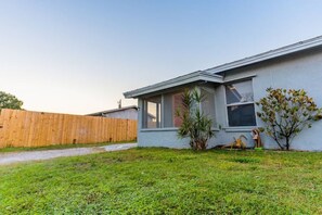 A single-story house with a front yard, a wooden fence, and a small tree. - The Orange Door - Coastal Escape (Stuart)