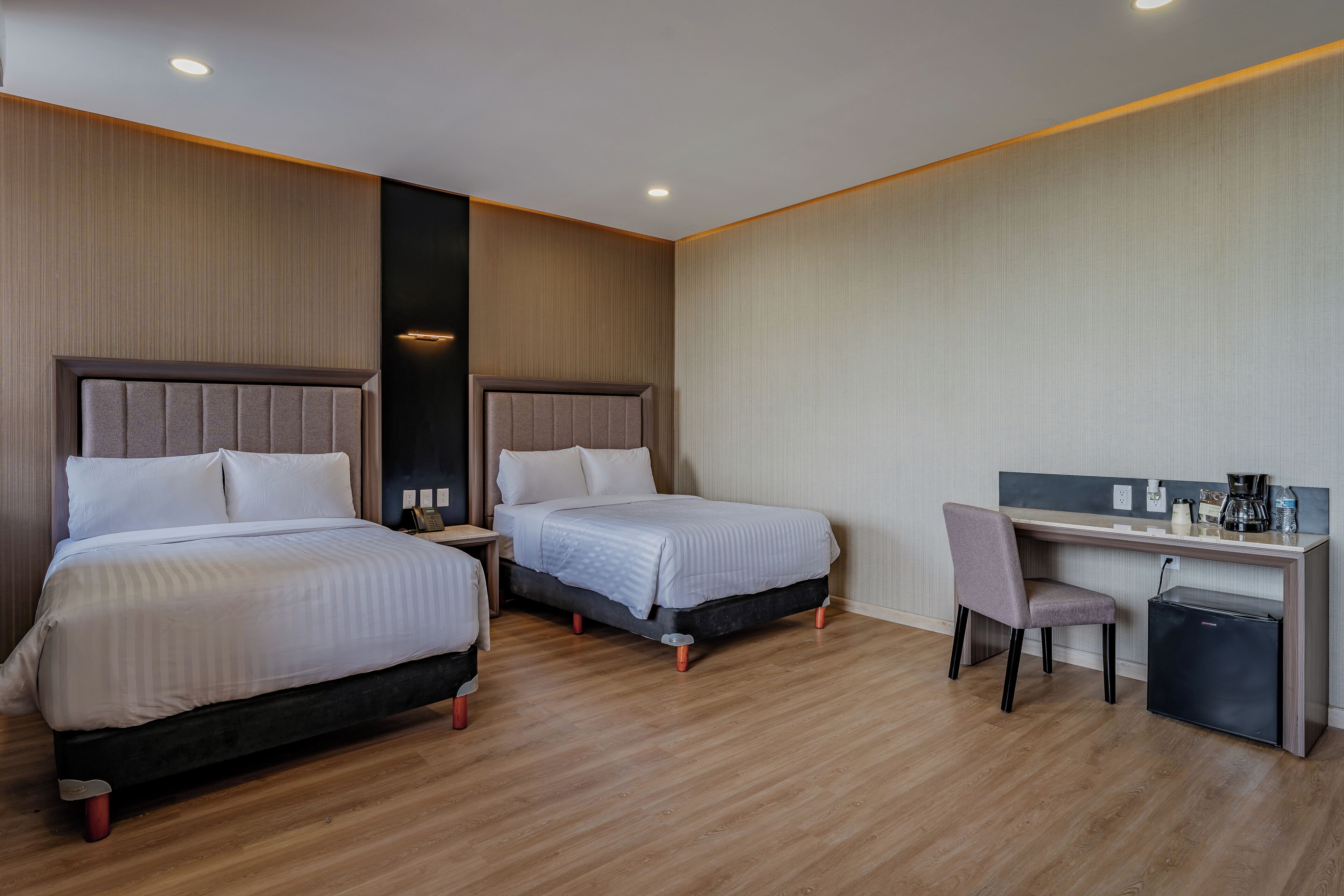A hotel room with two beds, a desk, and a chair.
