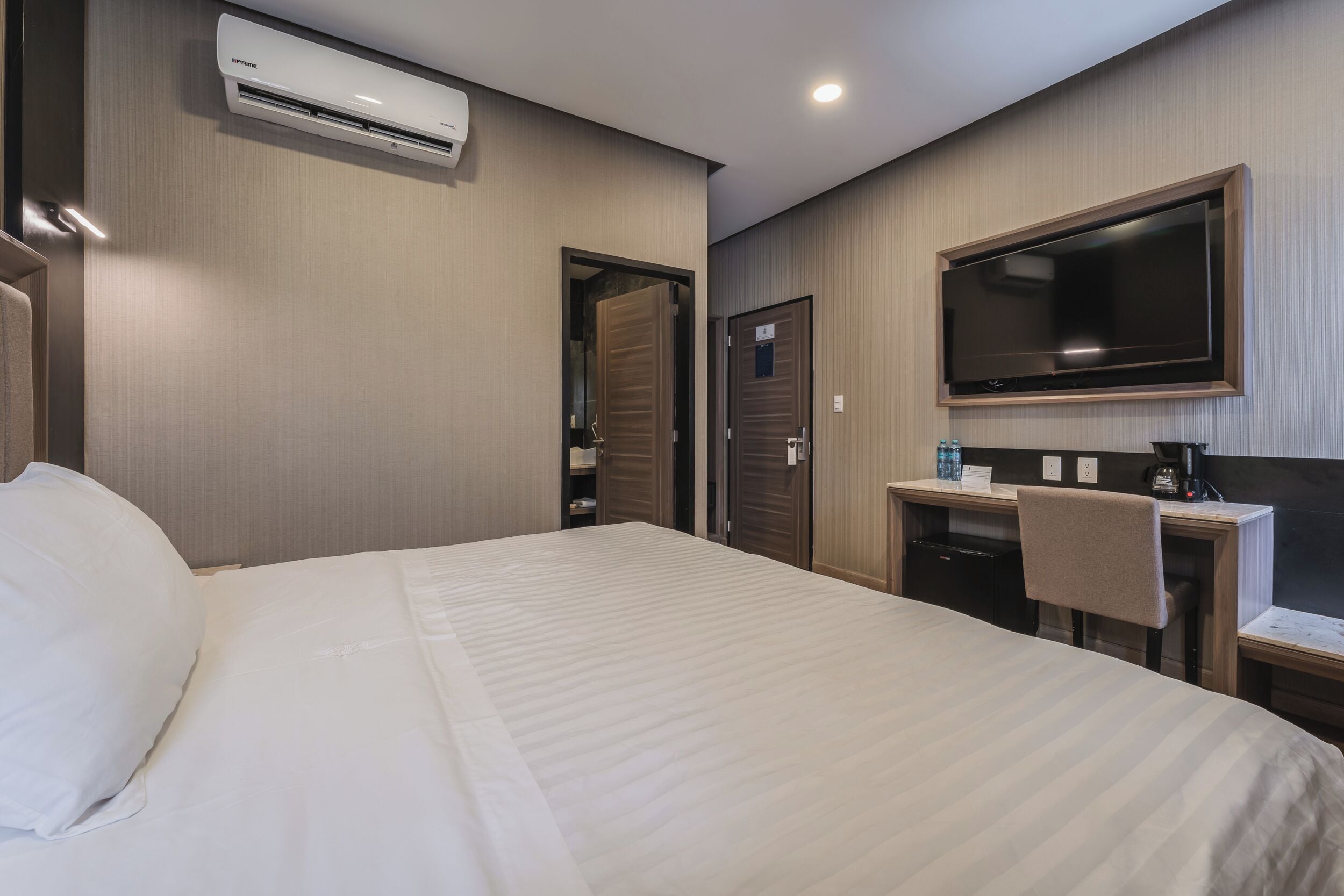 Une chambre d’hôtel équipée d’un lit, d’un bureau, d’une chaise, d’une télévision et d’un appareil de climatisation.