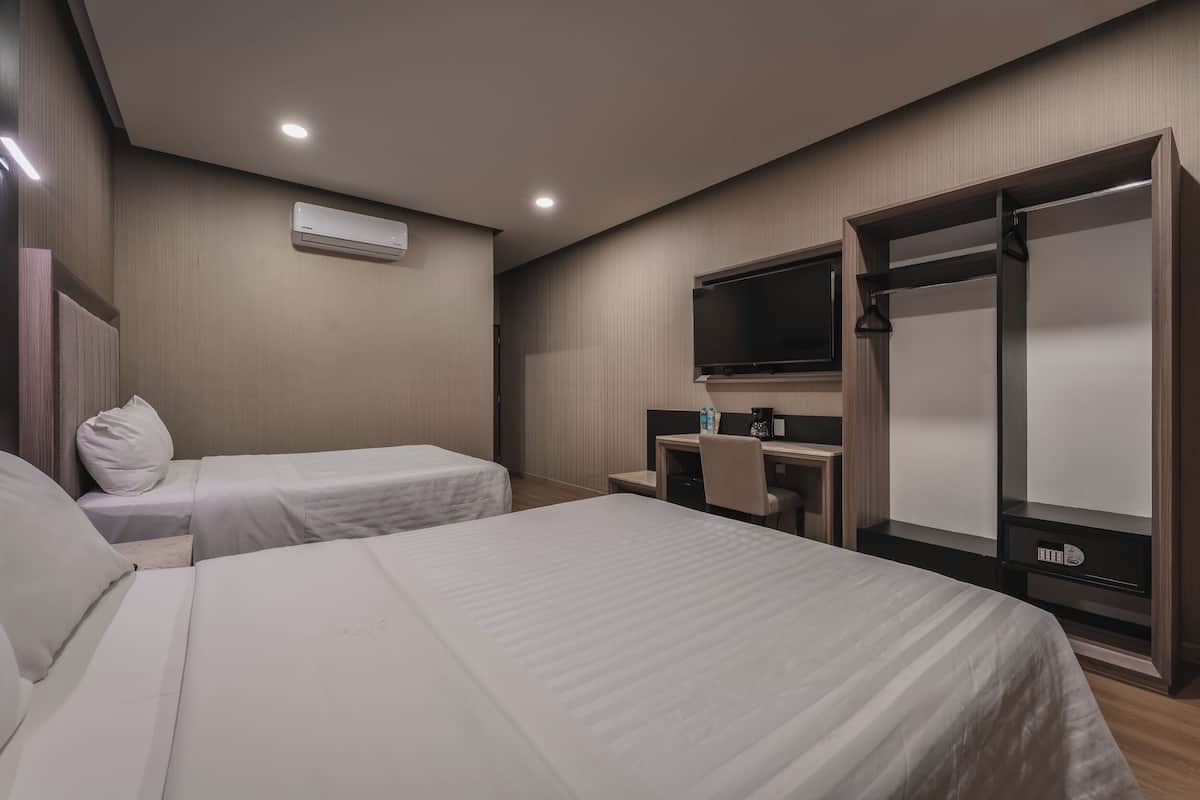 A hotel room with two single beds, a desk with a chair, a TV, and a wardrobe.