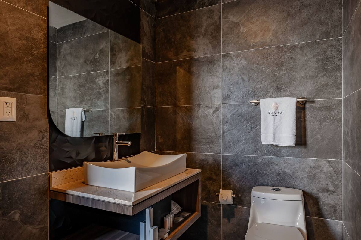 A modern bathroom with a large mirror, a white sink, and a toilet.