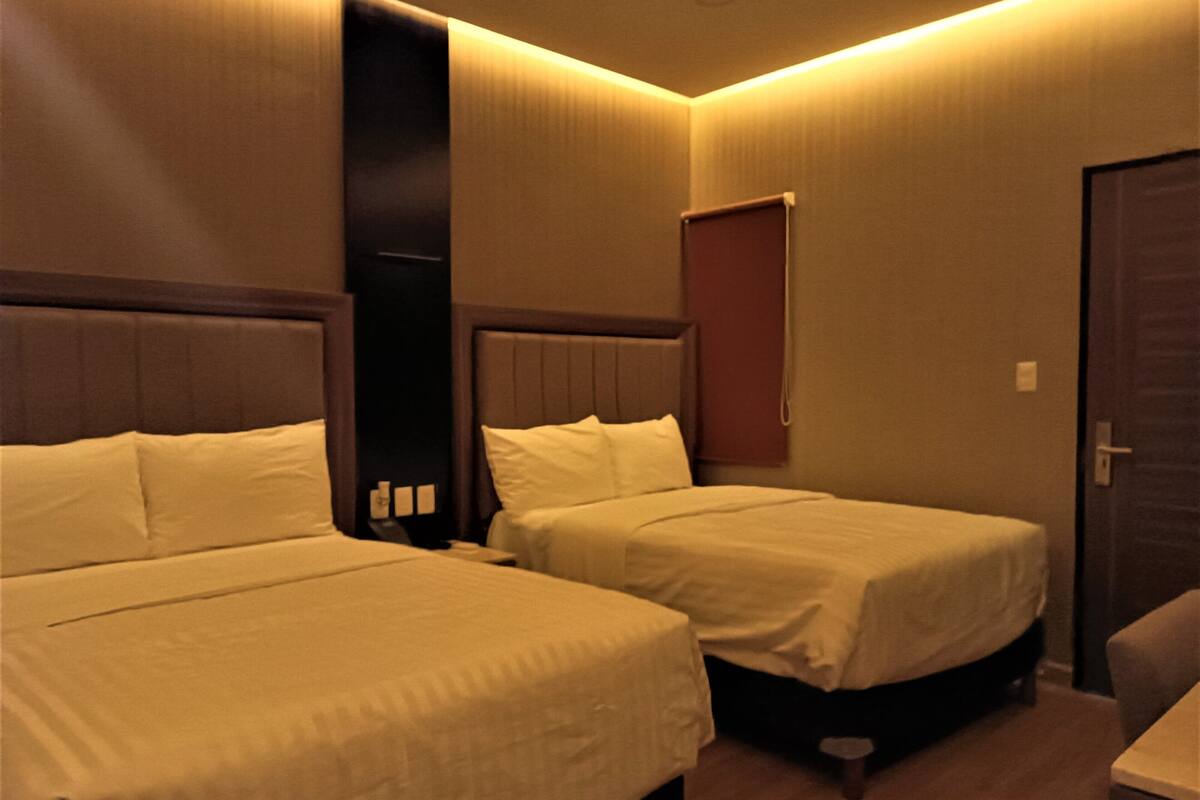 A hotel room with two beds, a door, and a small table.
