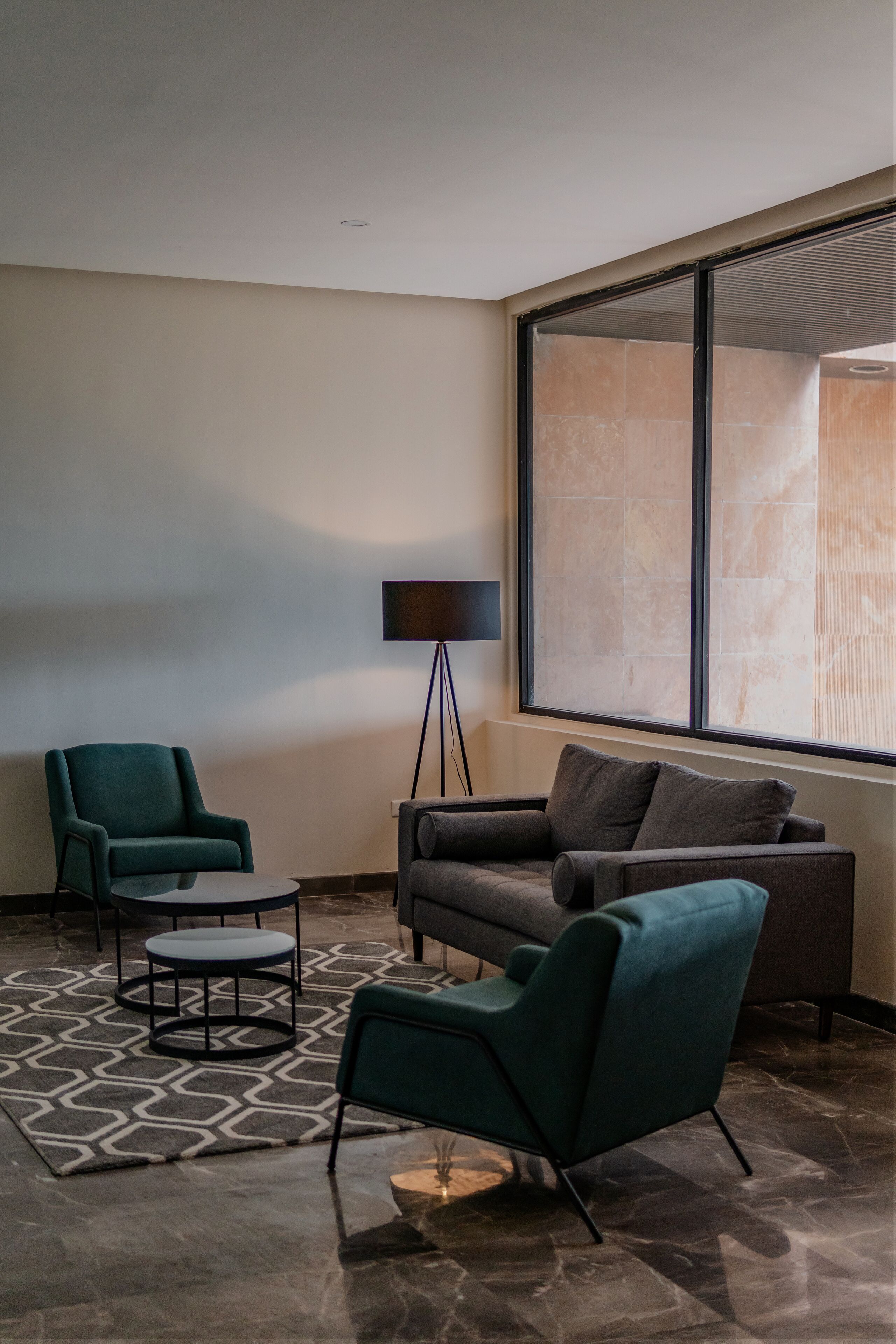 A modern living room with a sofa, two armchairs, a small coffee table, and a floor lamp.