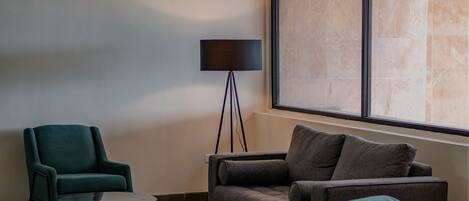 A modern living room with a sofa, two armchairs, a small coffee table, and a floor lamp.