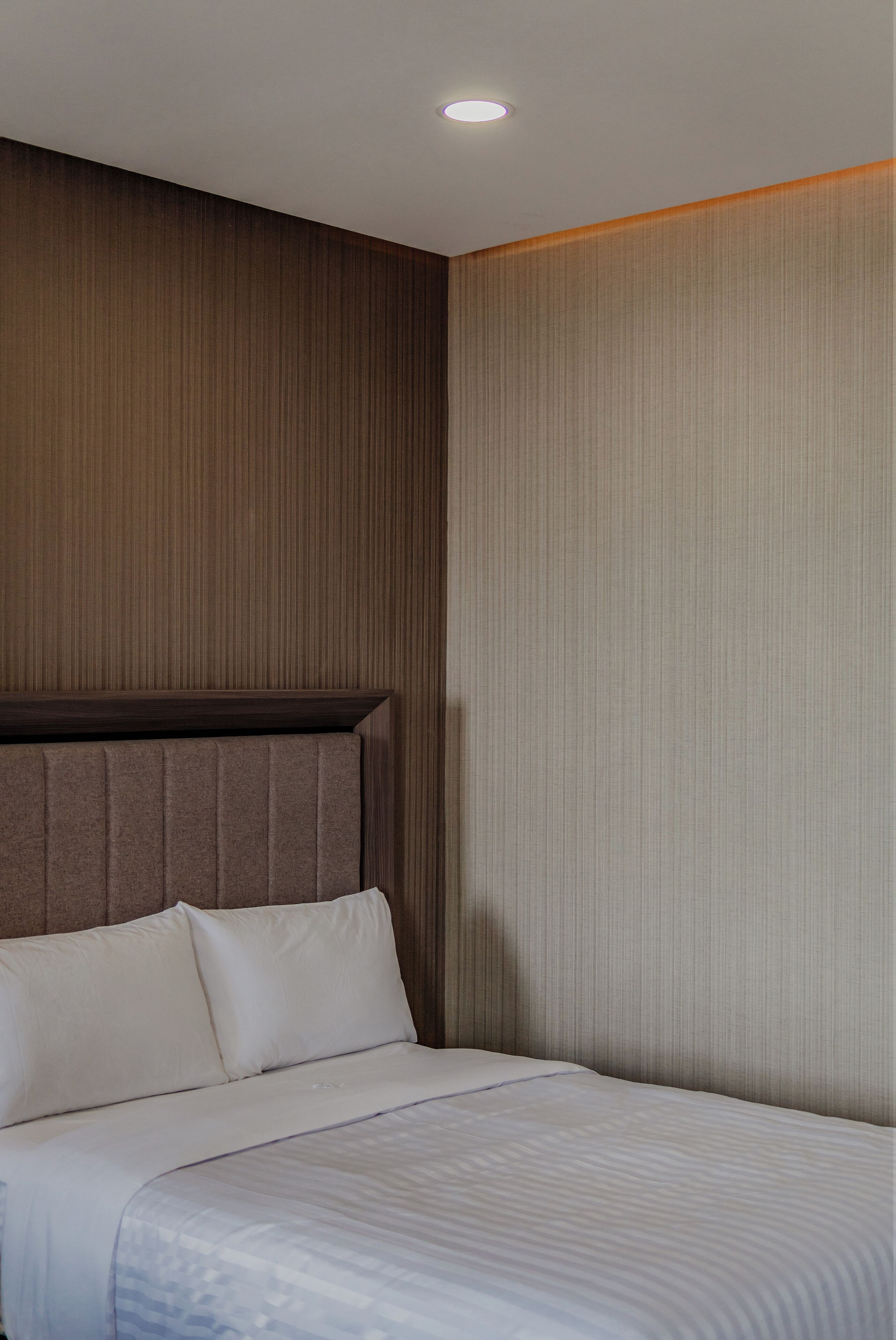 A hotel room with a large bed, a wooden headboard, and a textured wall.