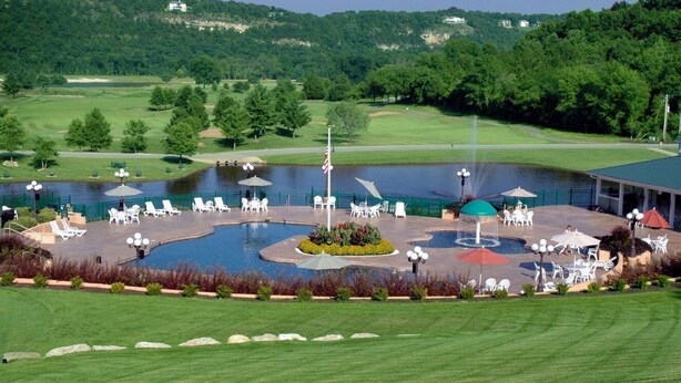 Ein Golfplatz mit Schwimmbad, Liegestühlen und einer Laube.
