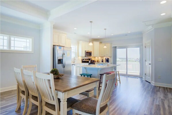 A spacious kitchen with white cabinets, a central island, and pendant lighting.