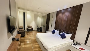 Una habitación de hotel moderna con una cama grande, un televisor, un escritorio y una silla.
