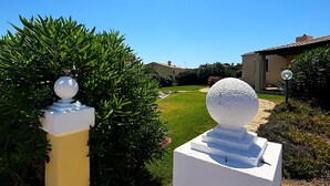 A gated entrance with a spherical finial, a stone wall, and a clear sky. - Villa Claudia, private pool (Stintino)