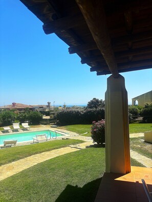 A pool area with lounge chairs, a clear view of the sea, and a well-maintained lawn. - Villa Claudia, private pool (Stintino)