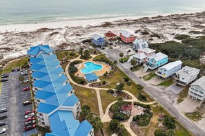 Vista aérea de un hotel costero con piscina, varias construcciones y una playa al fondo.