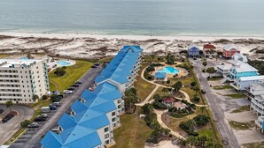 Un resort con un edificio lungo dotato di tetti blu, una piscina e vista sulla spiaggia.