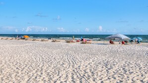 Una spiaggia sabbiosa con ombrelloni e lettini.