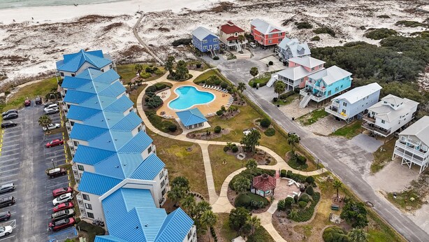 Vista aerea di un hotel sulla costa con piscina, diversi edifici e una spiaggia sullo sfondo.