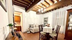 Un comedor con una mesa y sillas de madera, una bicicleta y una cocina al fondo.