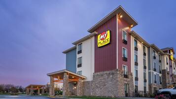 A multi-story hotel with a prominent 'My Place' sign, stone-clad exterior, and a covered entrance area.