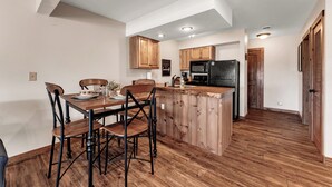 A kitchen with wooden cabinets, a dining table with chairs, a refrigerator, and a microwave. - Gorgeous Branson Condo, VIEWS, Hike and Fish on Property, Private Lake, 2 Pools! (Reeds Spring)