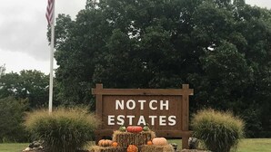 A wooden sign with "Notch Estates" written on it, surrounded by hay bales and pumpkins. - Gorgeous Branson Condo, VIEWS, Hike and Fish on Property, Private Lake, 2 Pools! (Reeds Spring)