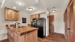 A kitchen with wooden cabinets, a black refrigerator, and a wooden island. - Gorgeous Branson Condo, VIEWS, Hike and Fish on Property, Private Lake, 2 Pools! (Reeds Spring)