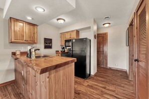 A kitchen with wooden cabinets, a black refrigerator, and a wooden island. - Gorgeous Branson Condo, VIEWS, Hike and Fish on Property, Private Lake, 2 Pools! (Reeds Spring)