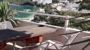 A terrace with a table and chairs overlooking a coastal area with buildings and greenery. - Apartments Kamaki - Two Bedroom Apartment with Balcony and Sea View (Gradac)