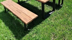 Une maison bleue avec une table de pique-nique en bois et des bancs dans la cour.